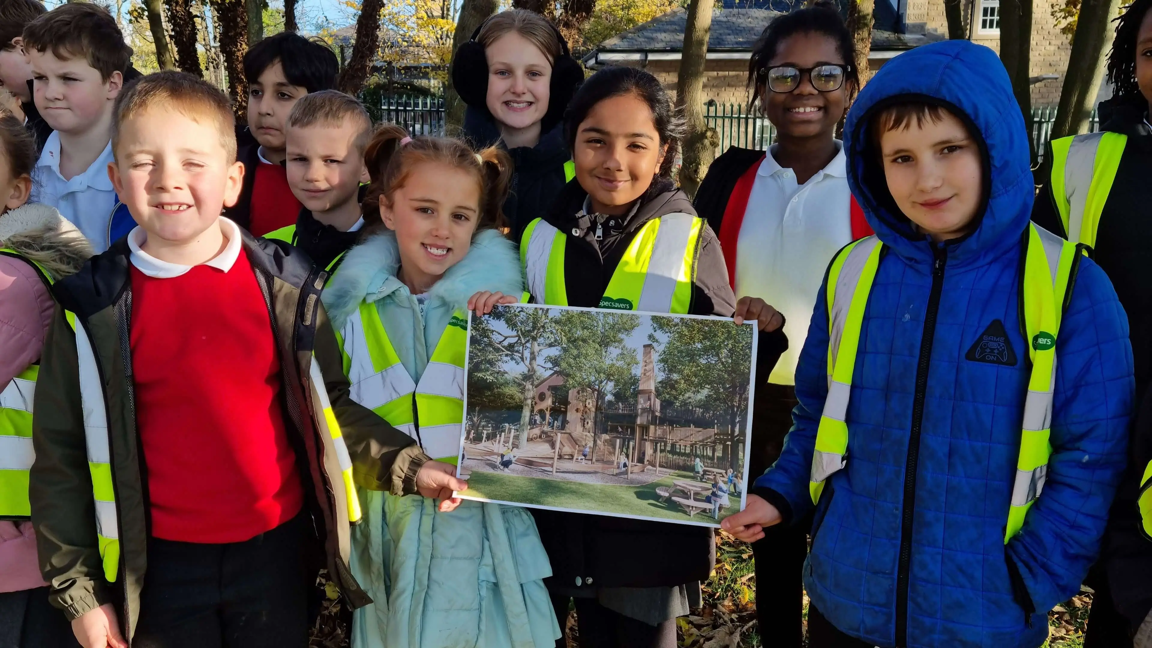 School children in high visibility jackets holding up a CGI image of Wagon Woods