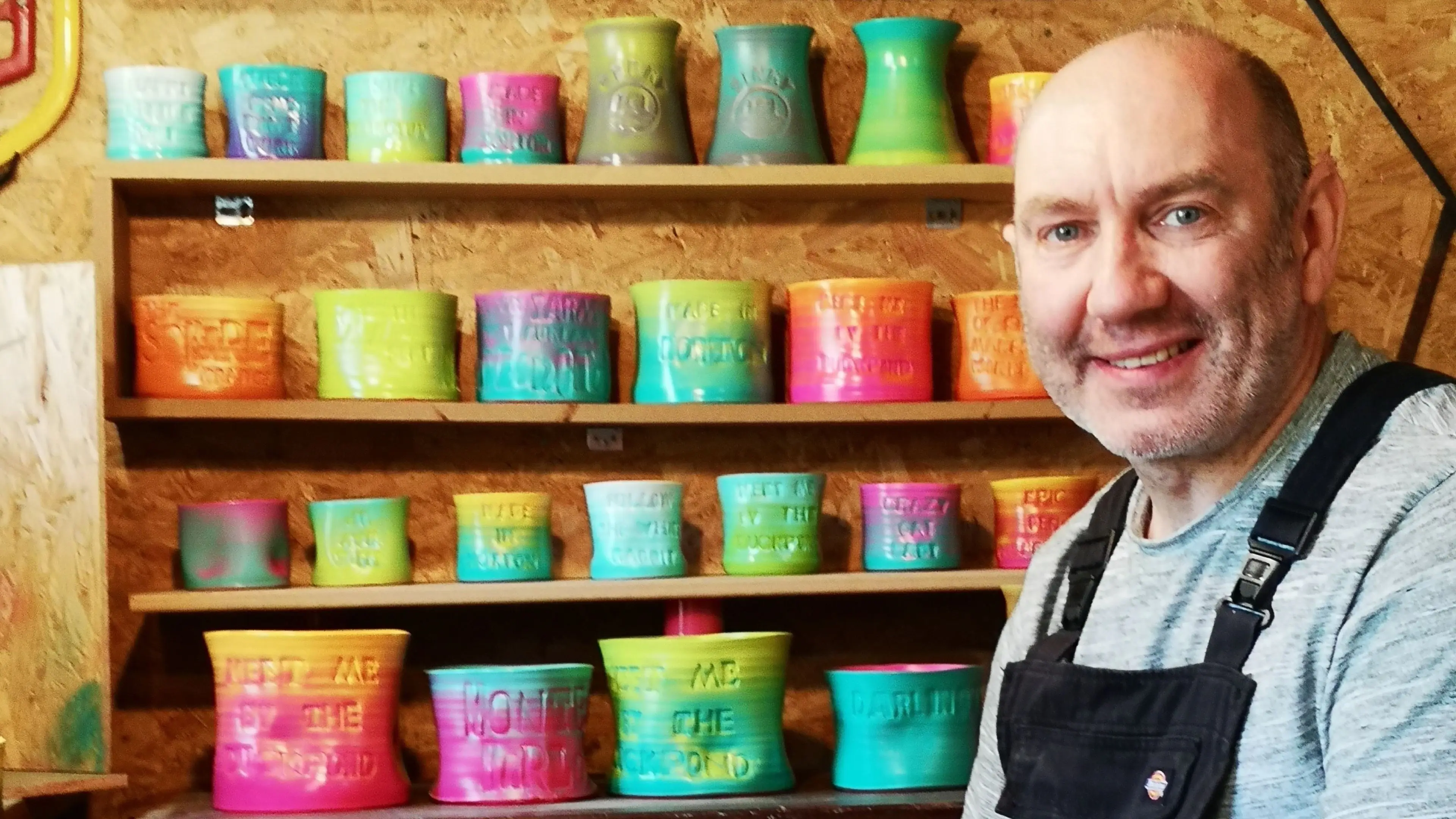 Man sat in front of shelves of multicoloured pots