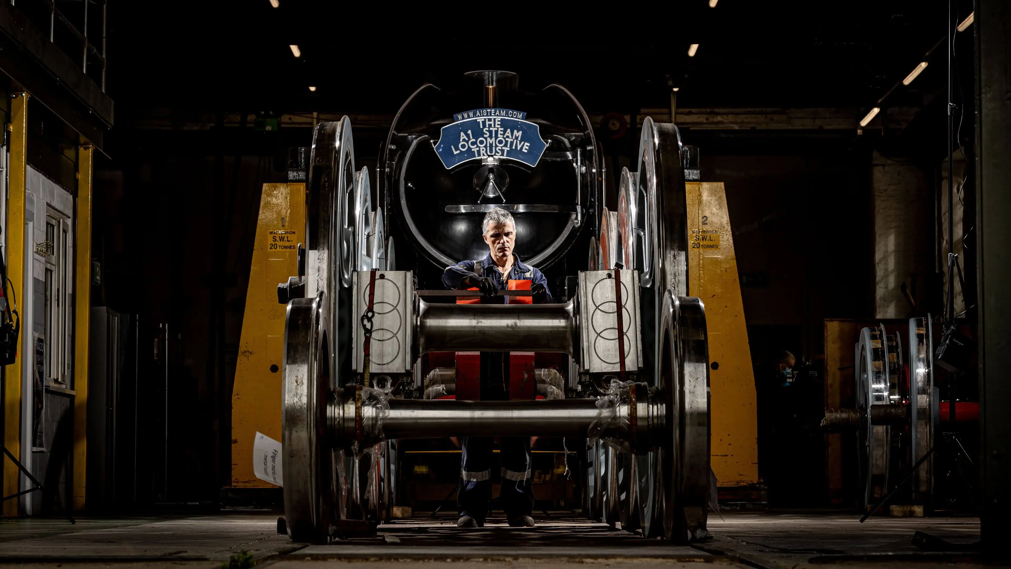 Man stood behind a large set of locomotive wheels