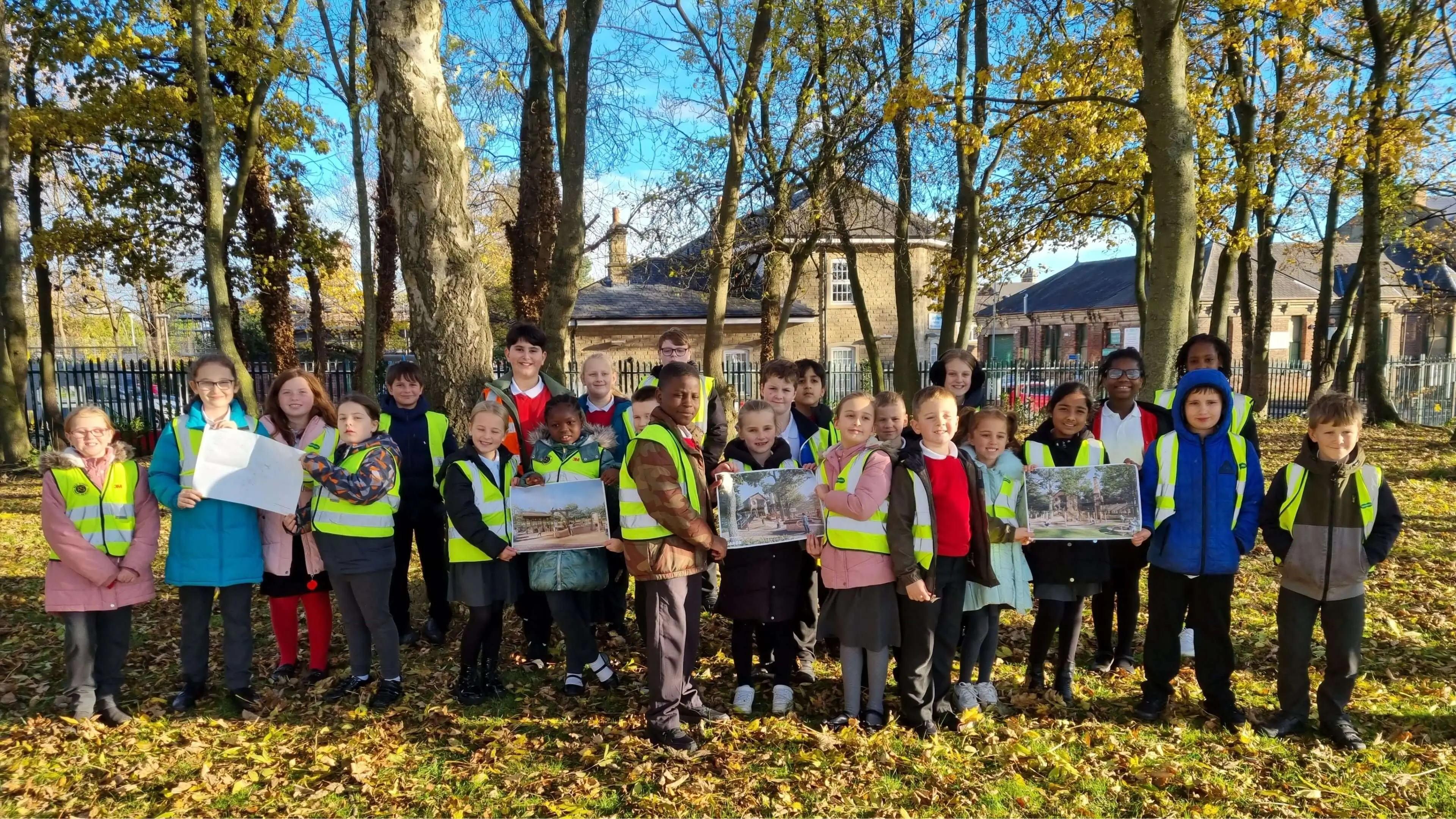 School children in high visibility jackets holding up CGI images of Wagon Woods